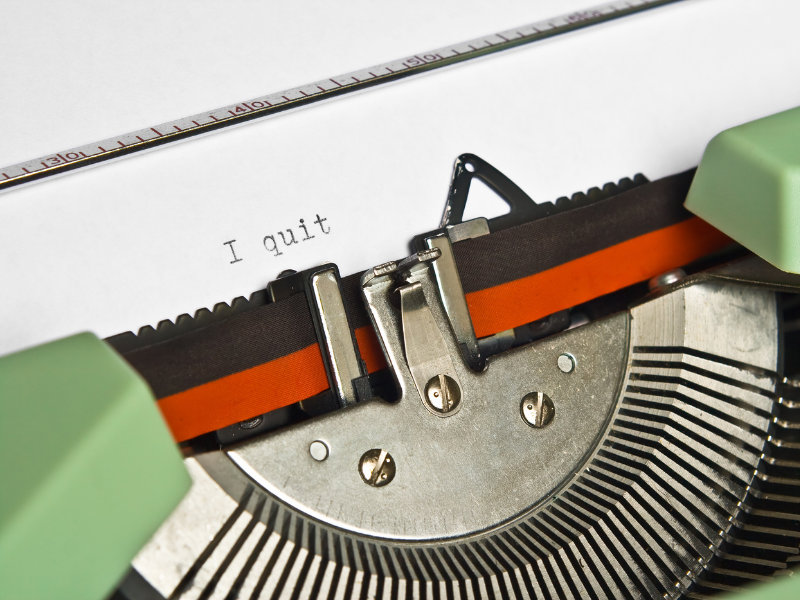 "Vintage typewriter with the words "I quit" typed on a white sheet of paper, representing resignation or a new beginning."